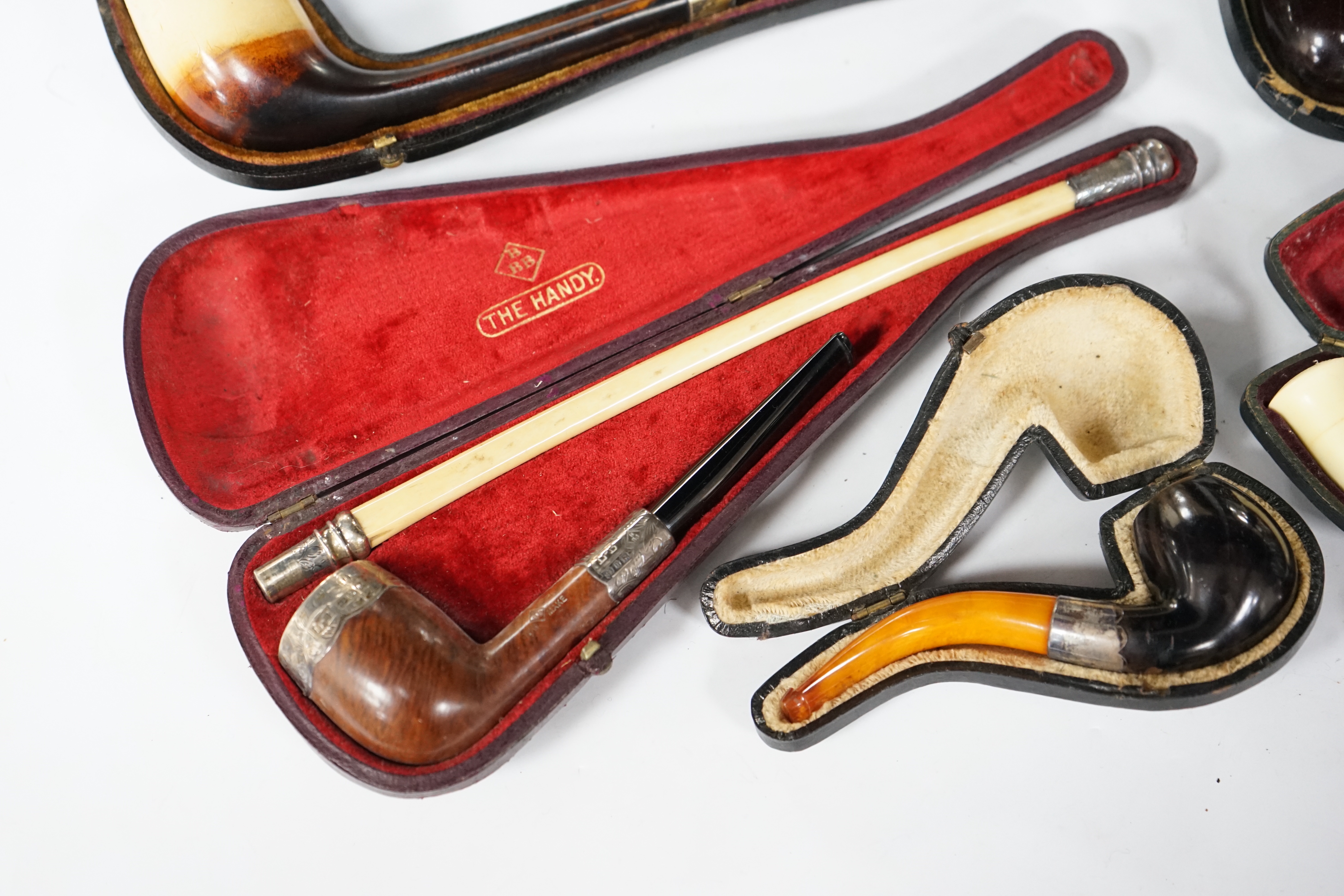 Seven cased pipes in varying sizes, some with amber mouthpieces, largest 19cm long